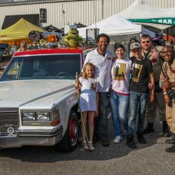 517 day attendees posing with people in Ghostbusters costume standing next to Ecto-1 replica car at 517 Day event