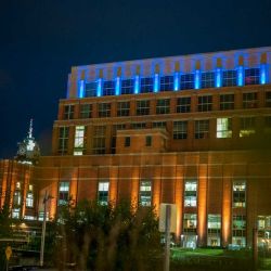 Picture of the BWL building at night with blue glowing lights and boji tower in the background